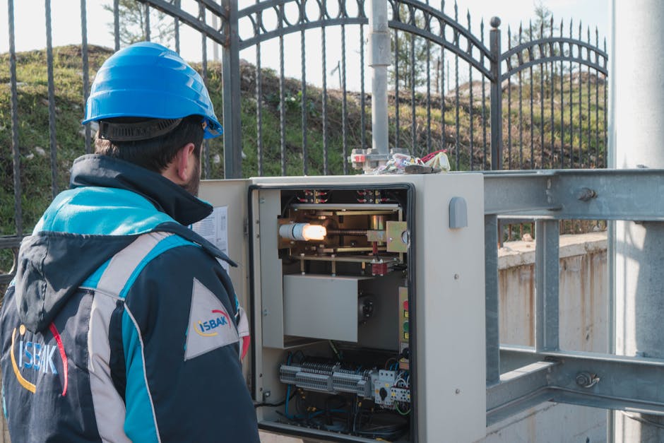 A professional electrician wearing a hard hat inspects an outdoor fuse box ensuring safety.